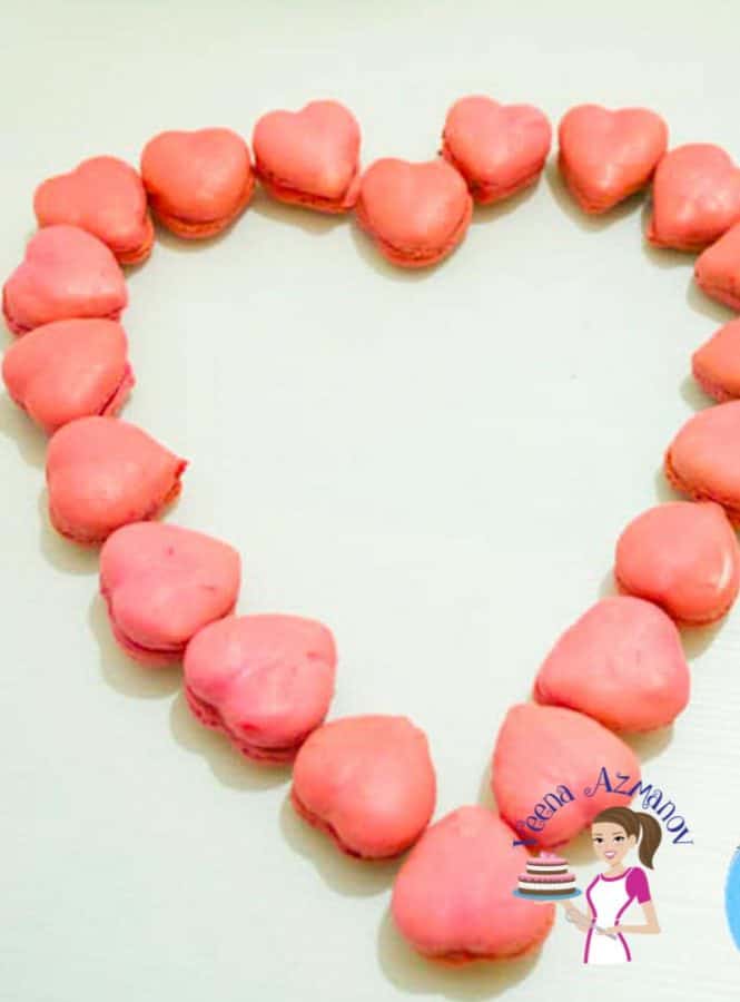 Heart-shaped macarons arranged in a heart shaped manner on a table.