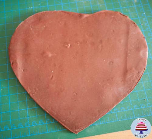 Progress photos of making a cake decorated to look like a heart-shaped box of strawberries coated with chocolate.