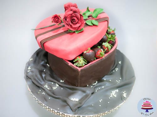 A cake decorated to look like a heart-shaped box of strawberries coated with chocolate.