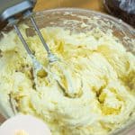A bowl and hand mixer whipping buttercream with egg yolks.