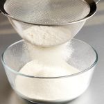 Sifting flour into a bowl.