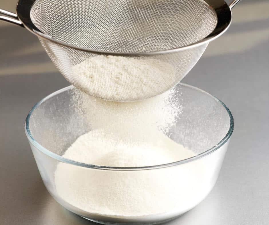 Sifting flour into a bowl.