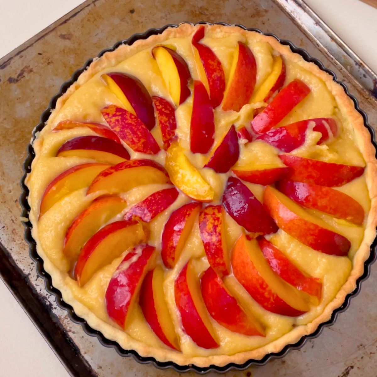 A tart crust filling with frangipani and nectarine slices.