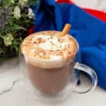 A glass cup with cinnamon hot chocoalte.