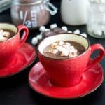 A red ceramic cup with hot chocolate and marshmallows.