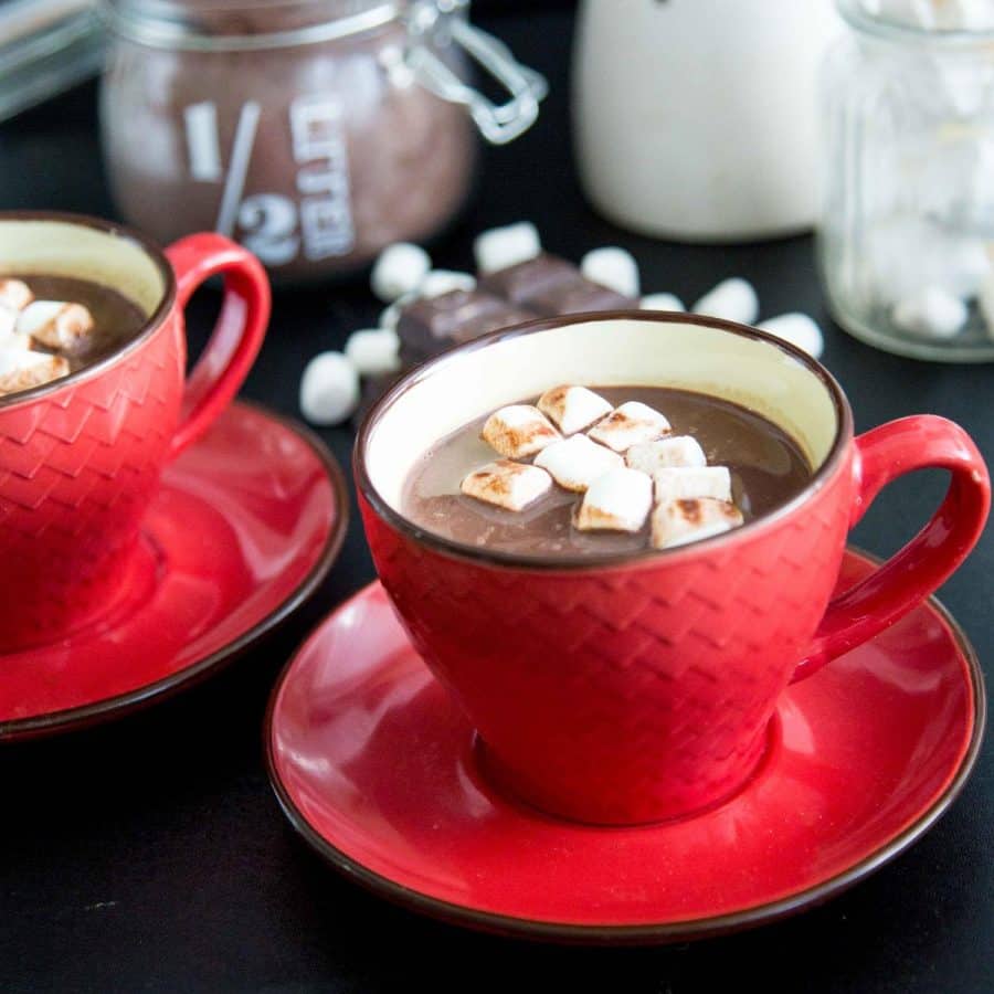 A red ceramic cup with hot chocolate and marshmallows.