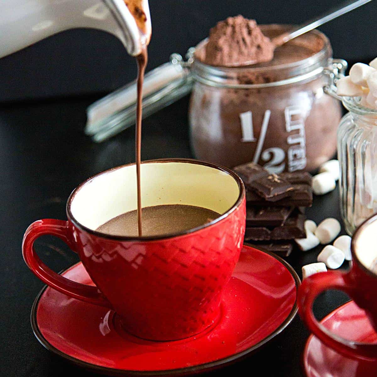 Pouring hot chocolate in a red ceramic cup.