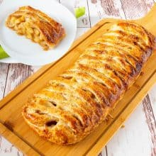 Braided puff pastry with apple pie on a wooden board.