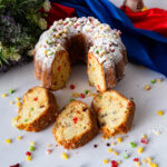 Slices of fruitcake with candied fruit showing bright orange, red, and green pieces.