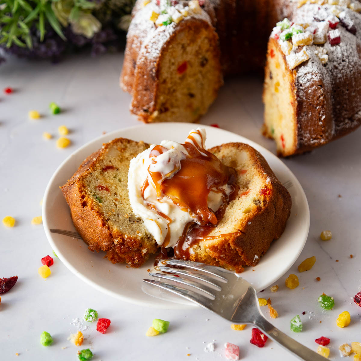 Slices of fruitcake with candied fruit showing bright orange, red, and green pieces.