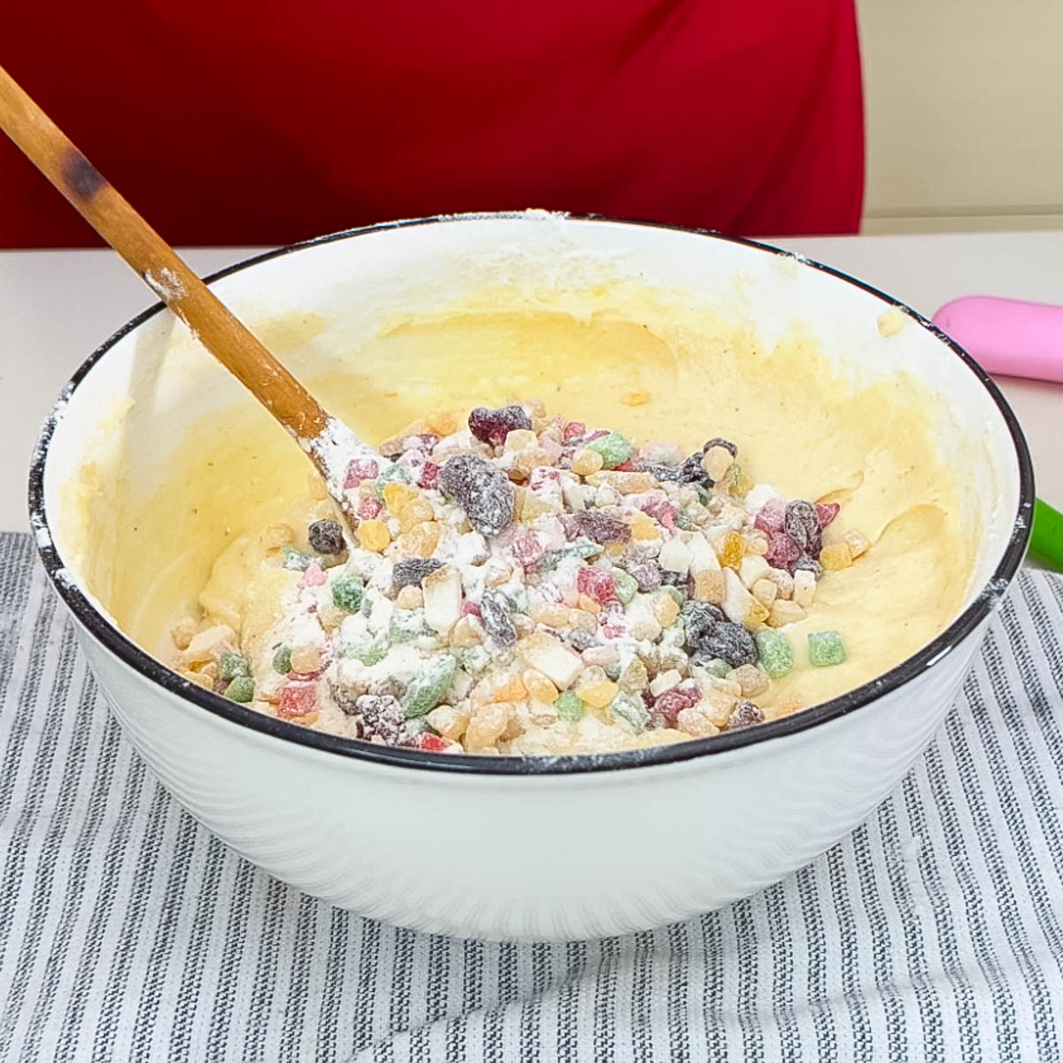 Candied fruit dusted with flour in a cake batter in a bowl.