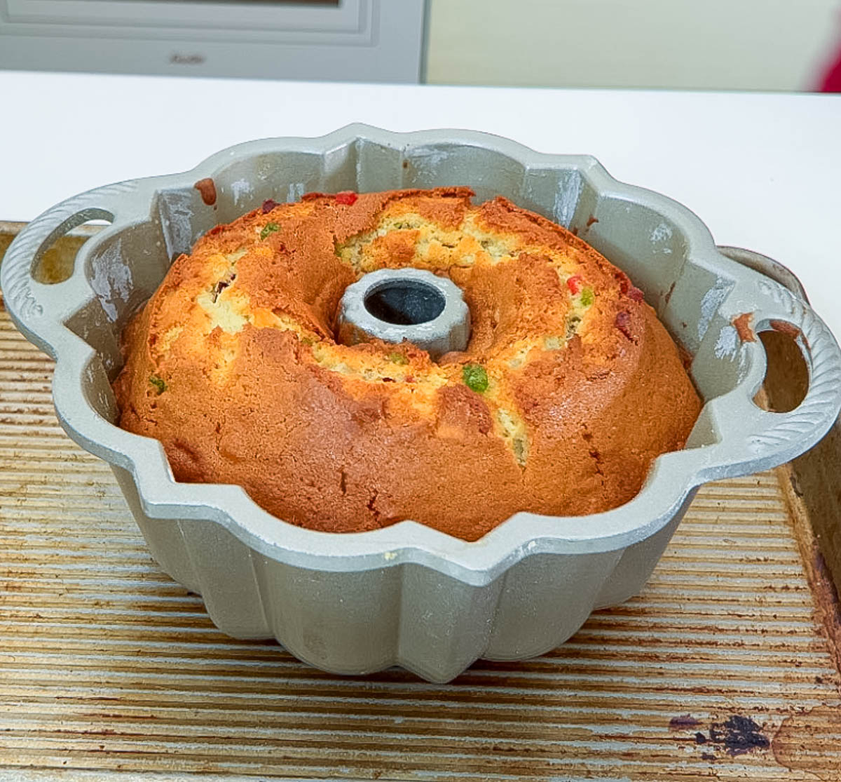 Fresh-baked candied fruit cake in bundt pan out of the oven.