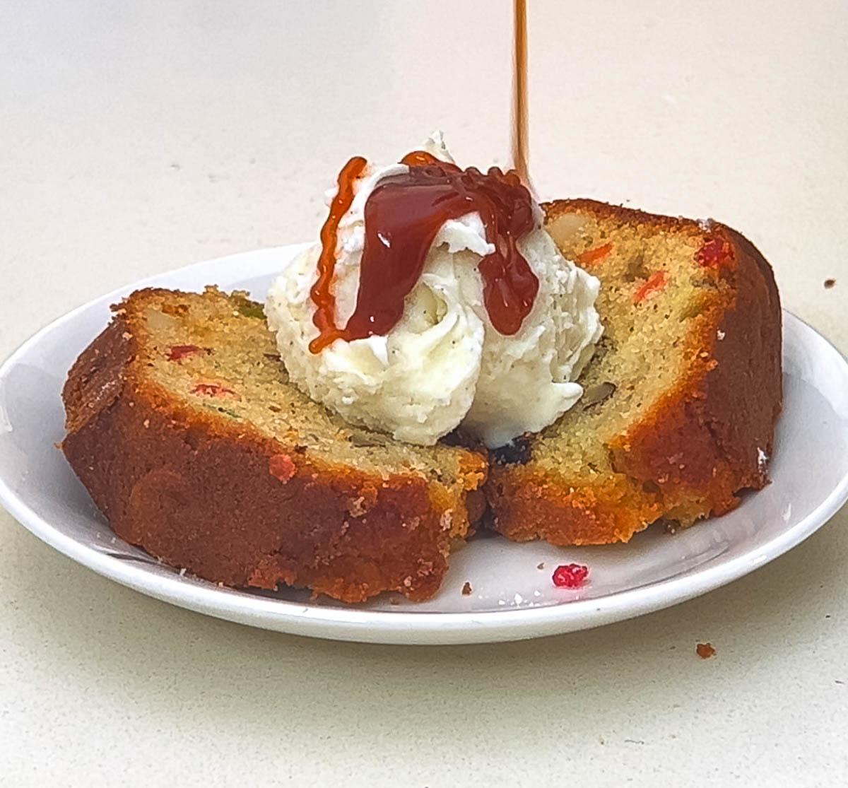 Drizzling caramel over ice cream on fruitcake.