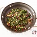 A skillet with kale and pine nuts