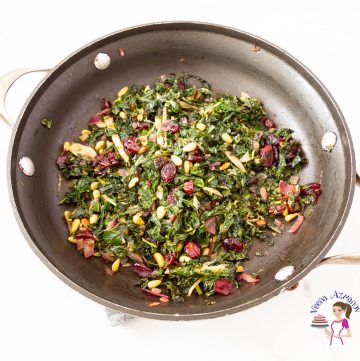 A skillet with kale sauteed with pine nuts