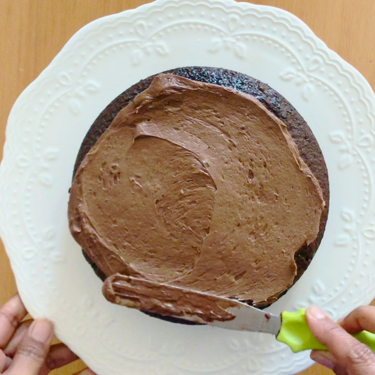 Frosting a chocolate cake with chocolate frosting.