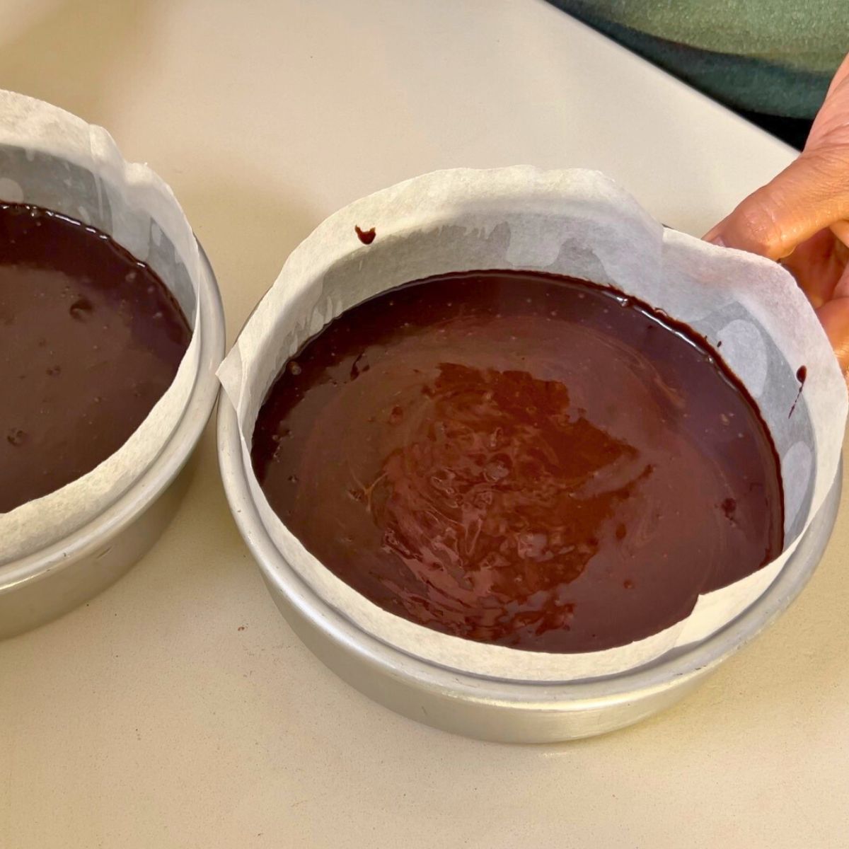 Two baking pans with chocolate cake batter.