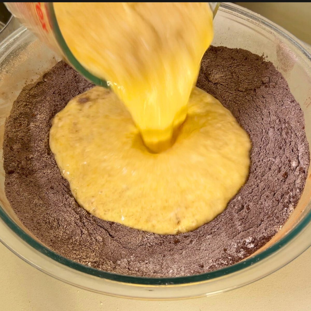 Adding wet to the dry ingredients in the chocolate batter.