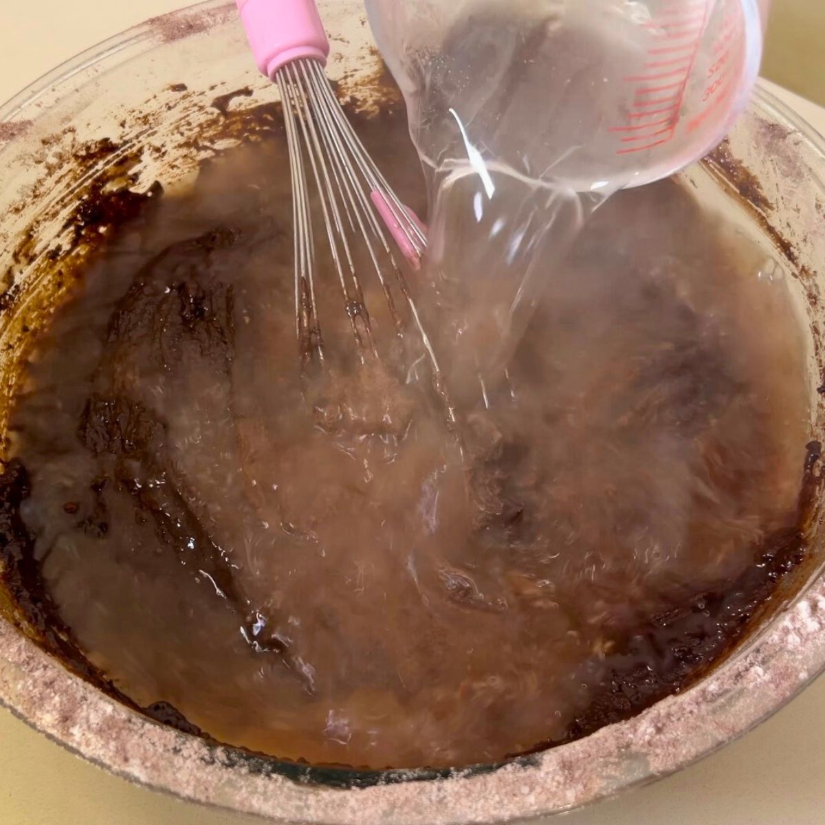 Adding hot water to the chocolate cake batter.