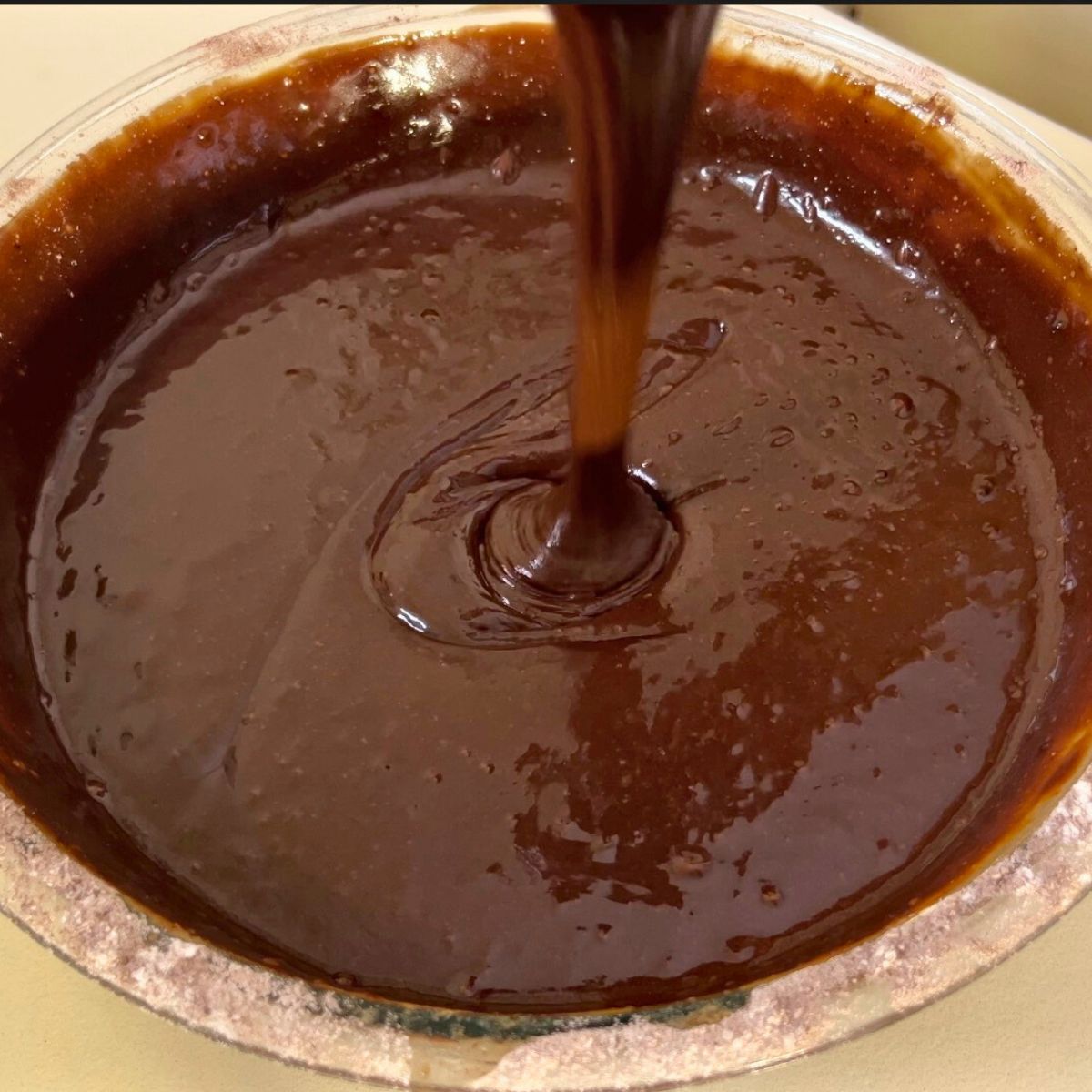 Chocolate cake batter in a glass bowl.