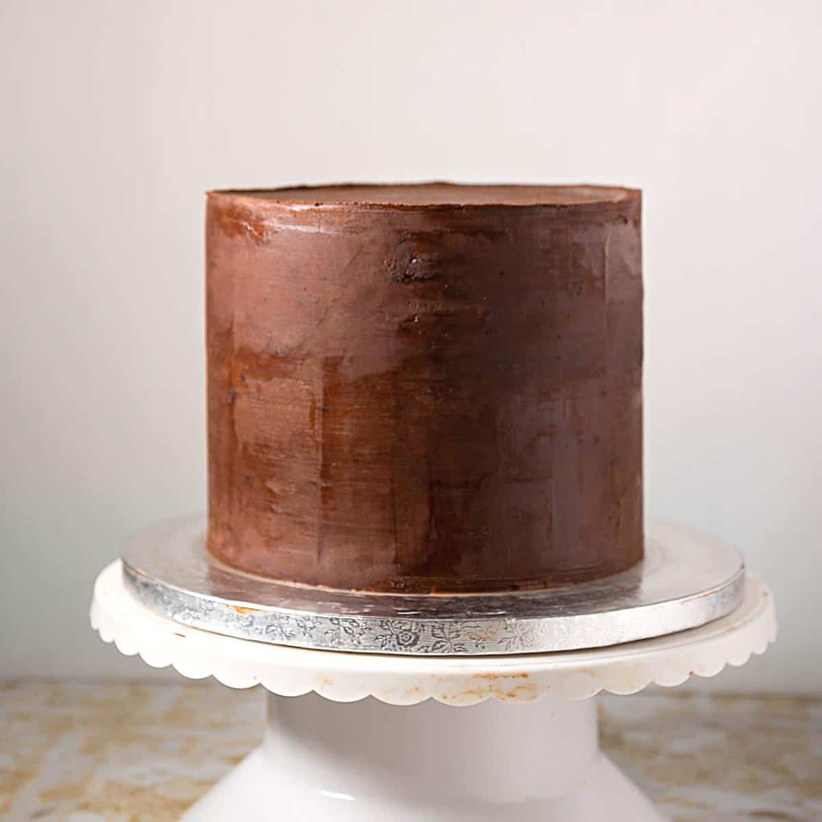 A cake frosted with sharp edges on ganache.