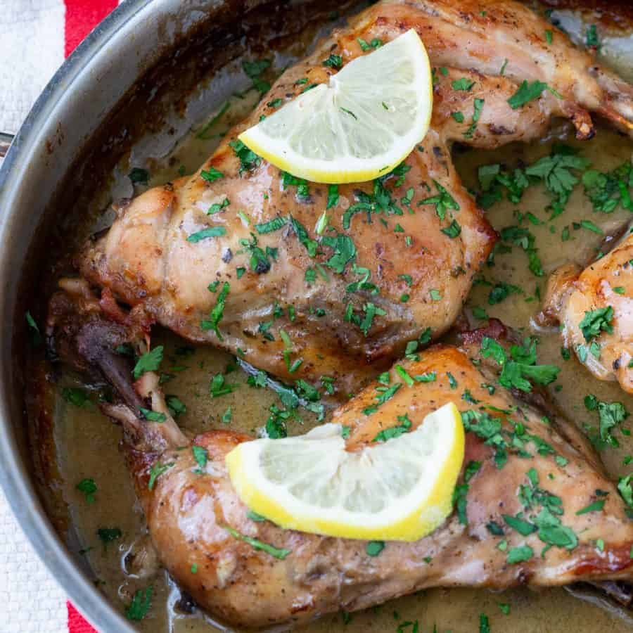 A skillet with lemon butter chicken quarters.