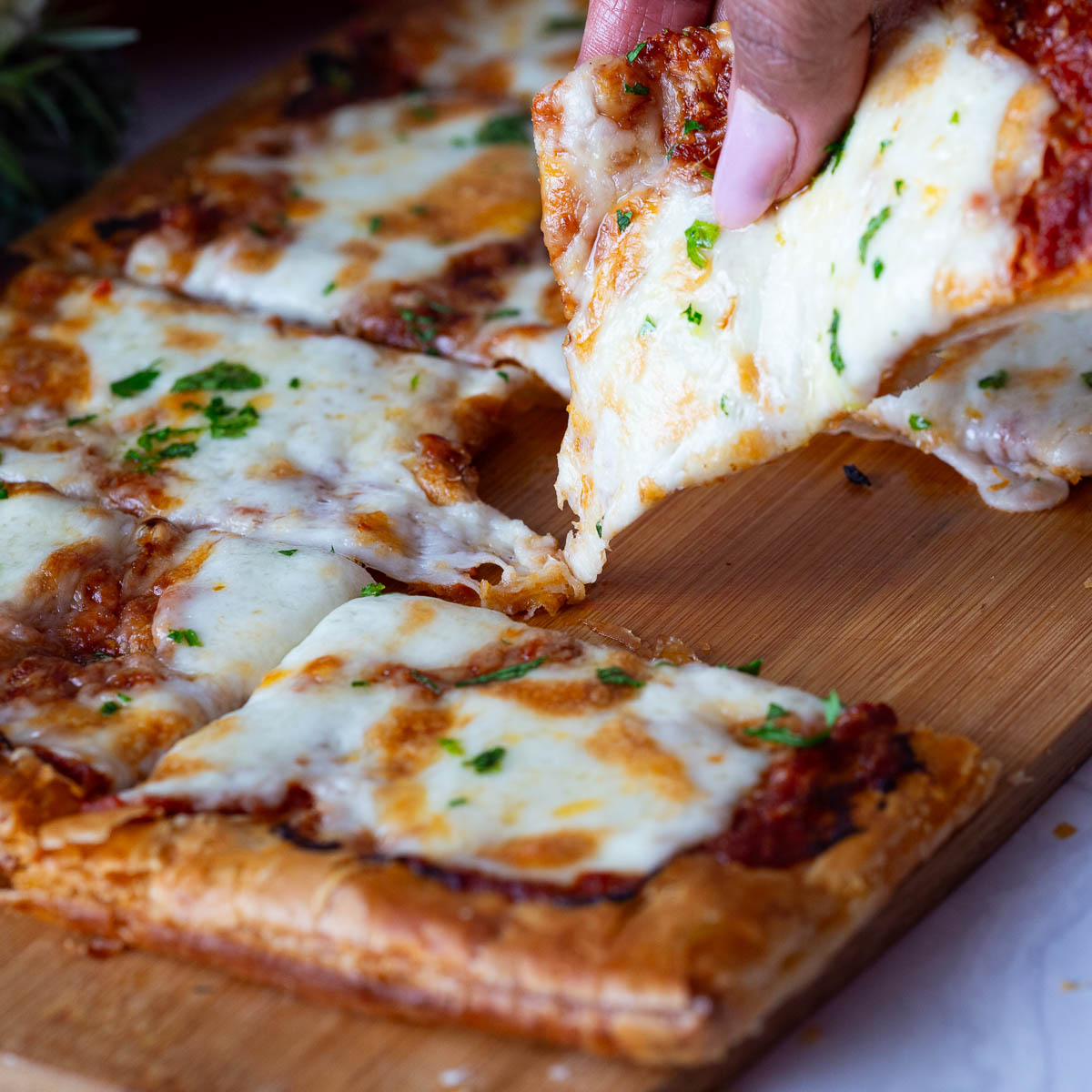 A wooden board with red pesto pizza and puff pastry.
