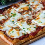 A wooden board with puff pastry pizza.