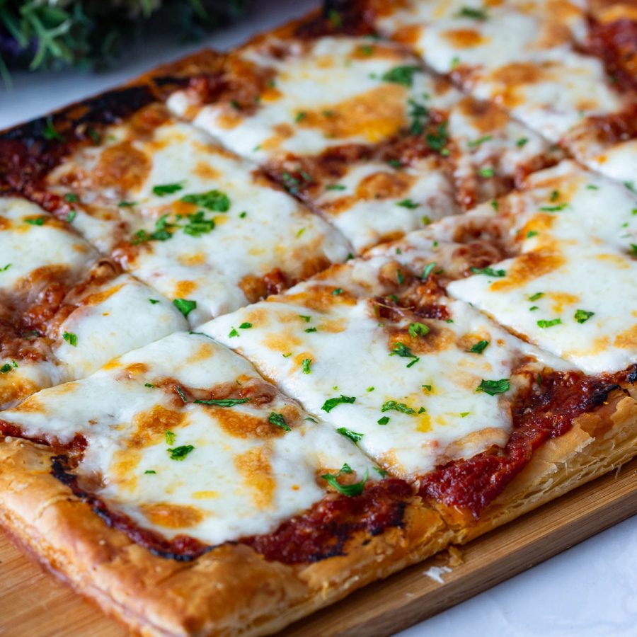 A wooden board with puff pastry pizza.