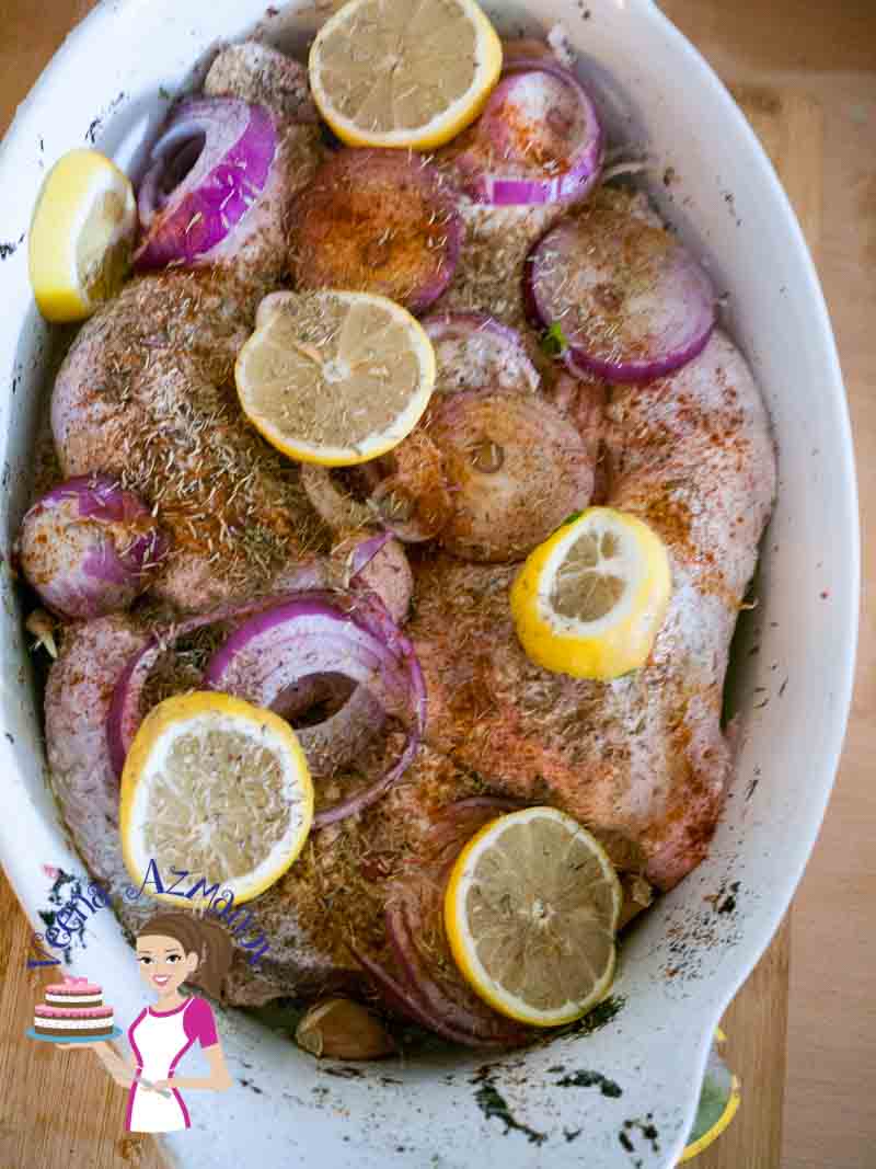 Unbaked chicken thighs with herbs and spices in a baking dish.