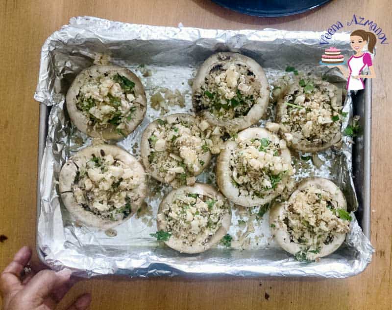 A baking tray with unbaked stuffed mushrooms.