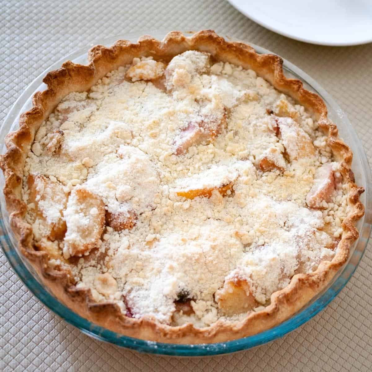 A pie with peaches on a table.