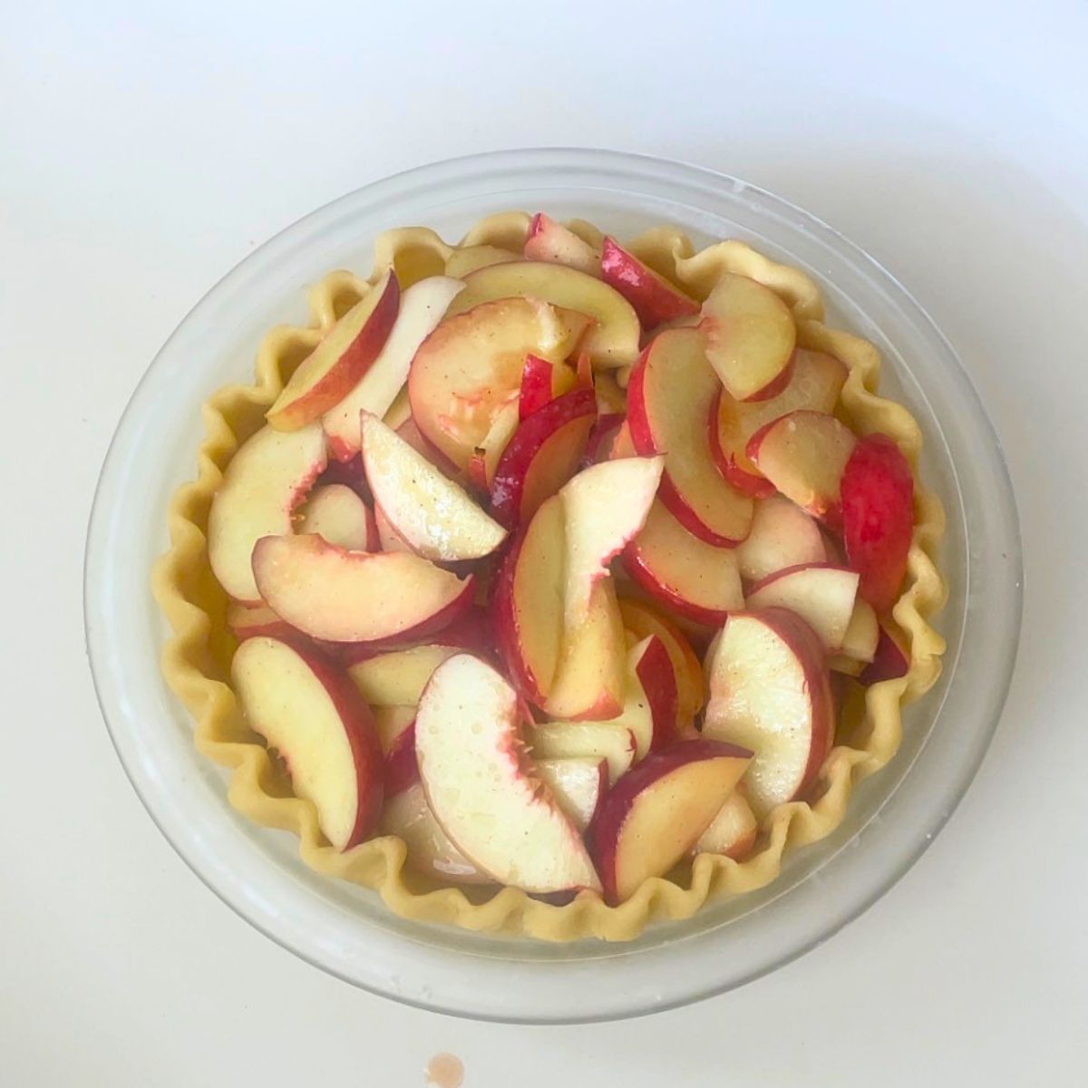 Fresh sliced peaches in a pie crust for baking.