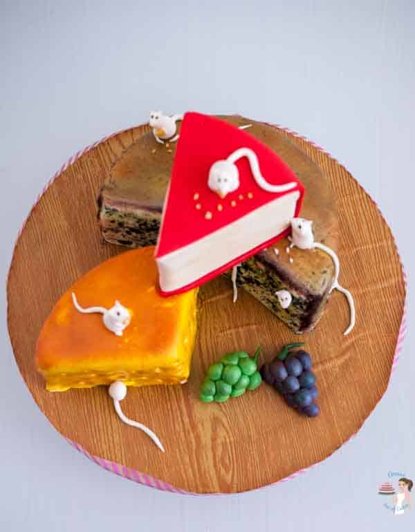 A cake decorated to look like three pieces of different cheeses.
