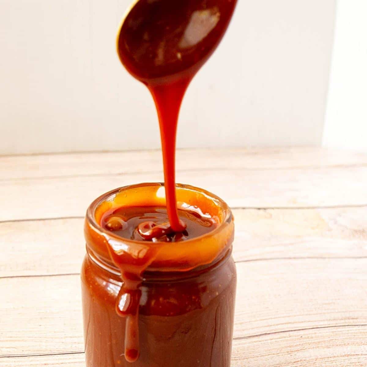 A mason jar and spoon with caramel sauce