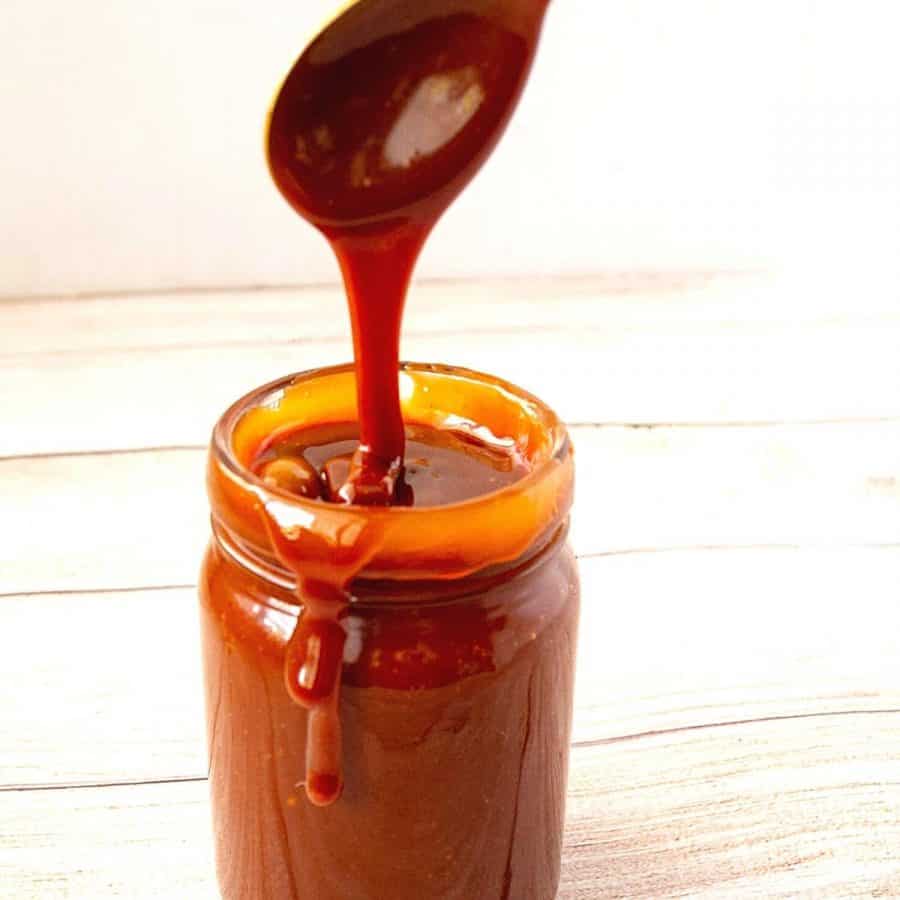 Pouring caramel sauce with a spoon and mason jar.