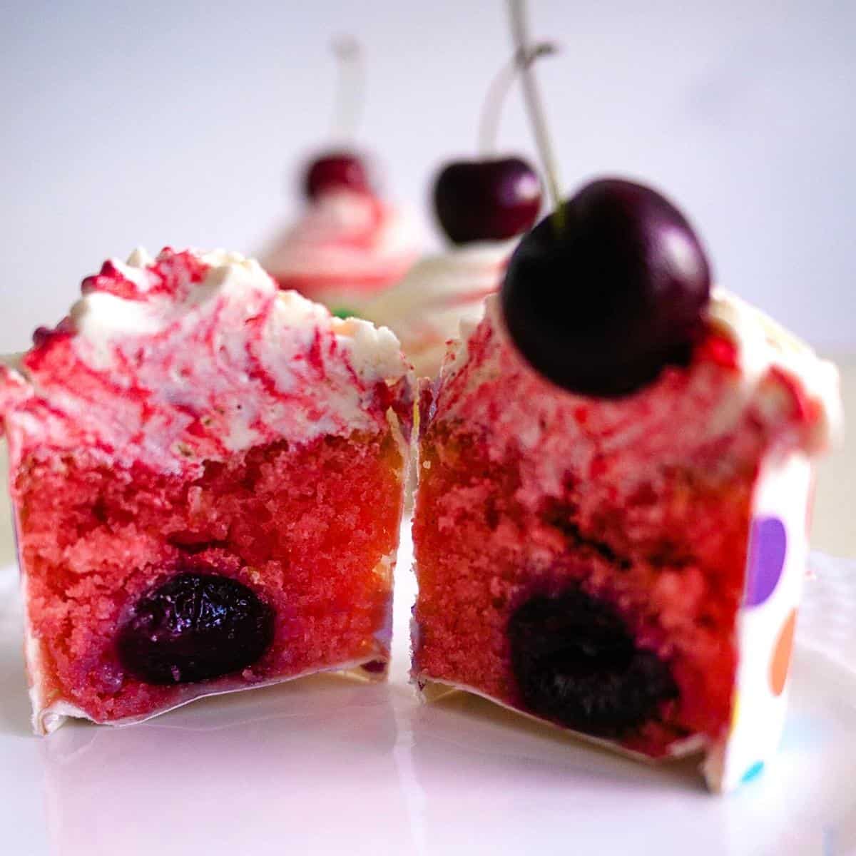 A cut cherry cupcake with fresh cherry.