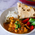 A plate with curry, rice, chapati and salad.