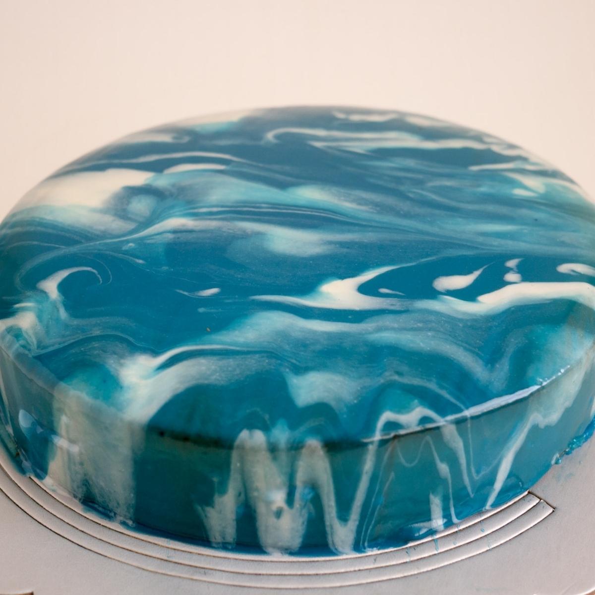 A mousse cake with mirror glaze on cake board.