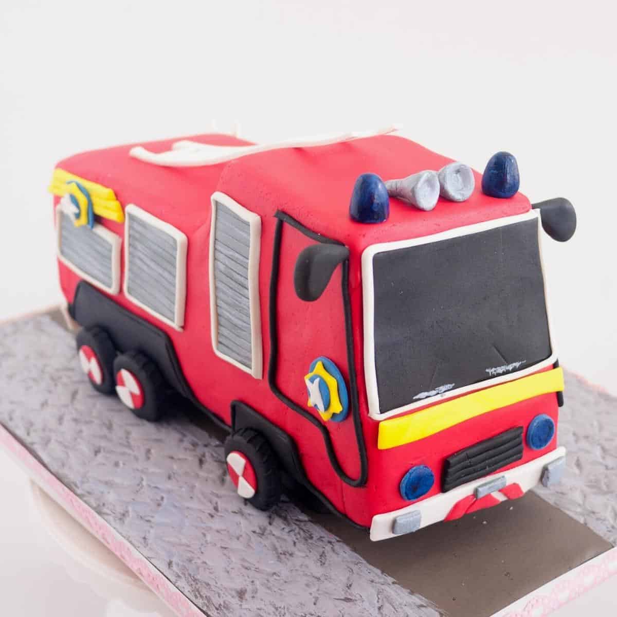 A frosted cake carve fire truck cake. on a cake board.