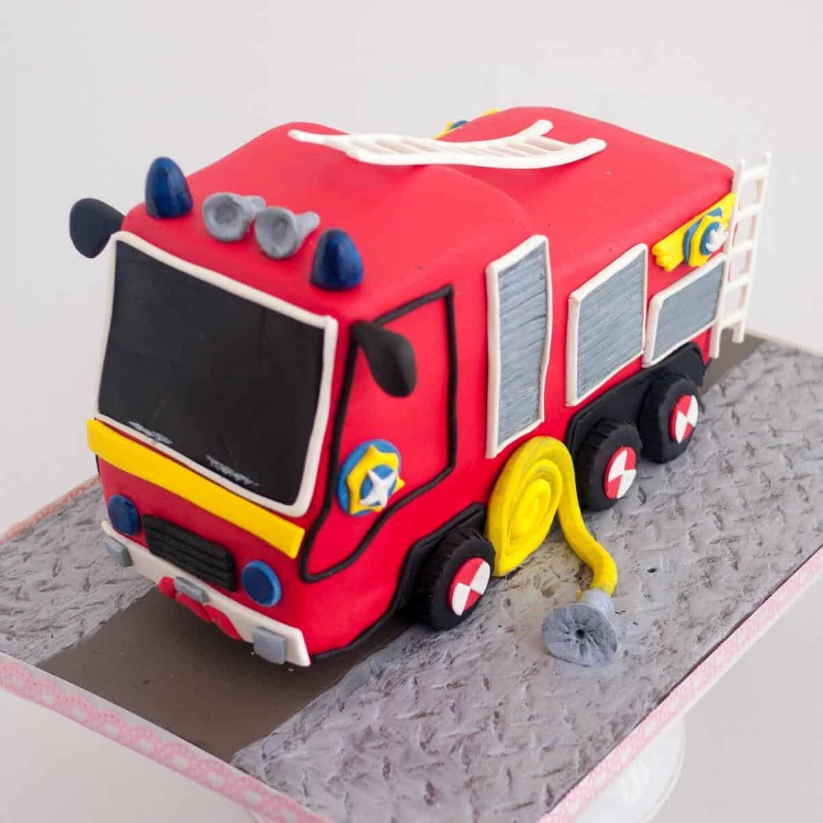 A fire engine cake on a cake board.