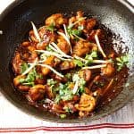 A wok with Asian ginger chicken and sauce.