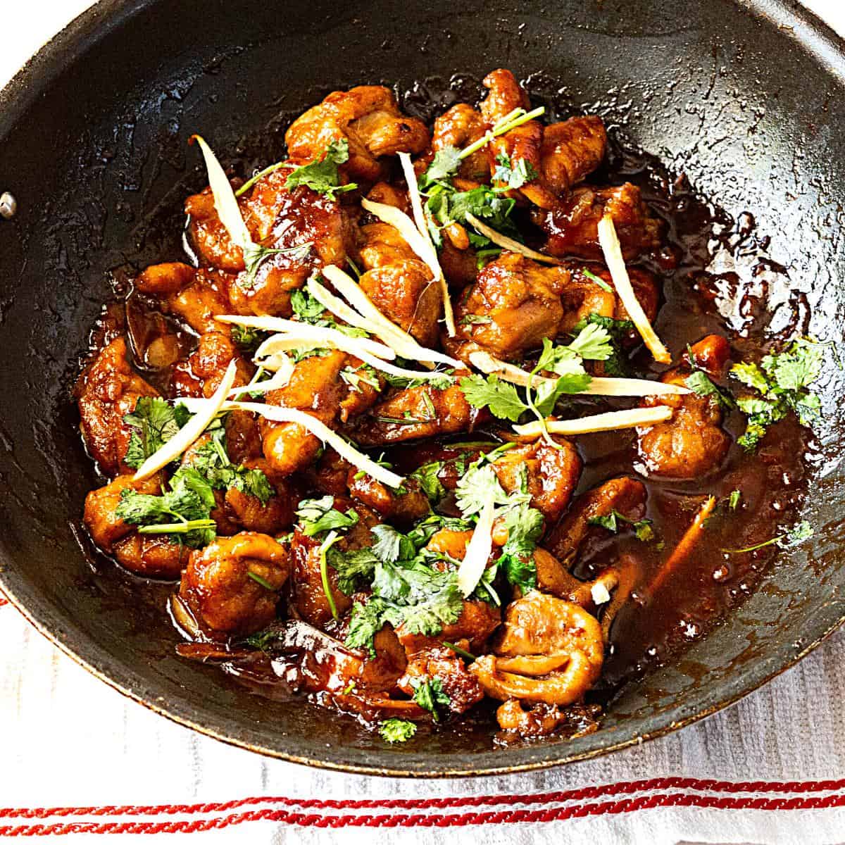 A wok with Asian ginger chicken and sauce.