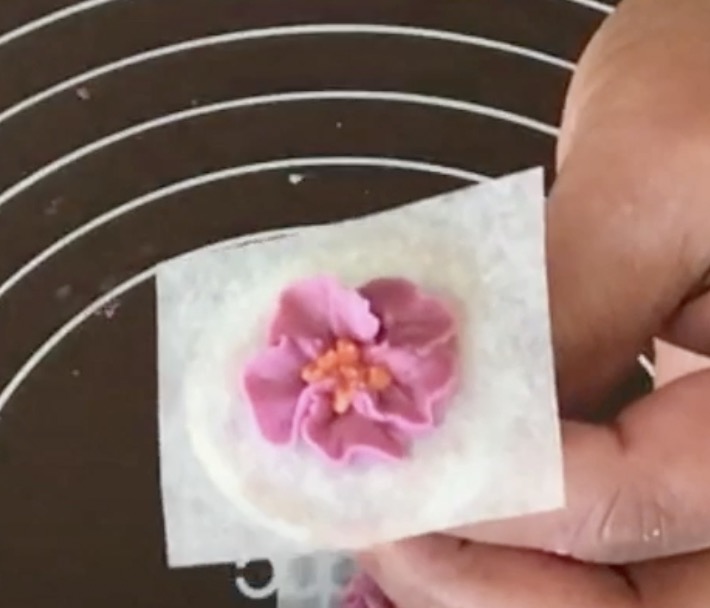 A piped buttercream blossom on a flower nail.