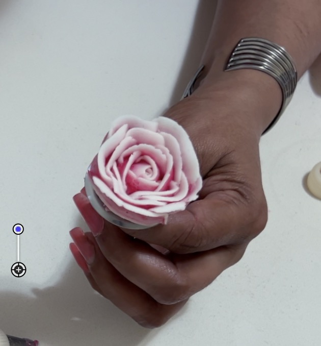 A piped white red rose on the flower nail.