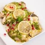 A serving platter with baked fish in cilantro marinade.