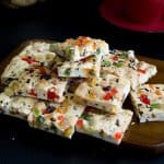 A stack of candied fruit shortbread squares on a board.