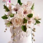 White sugar flowers on top of a wedding cake.