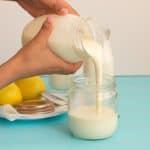 A person pouring evaporated milk into a jar.