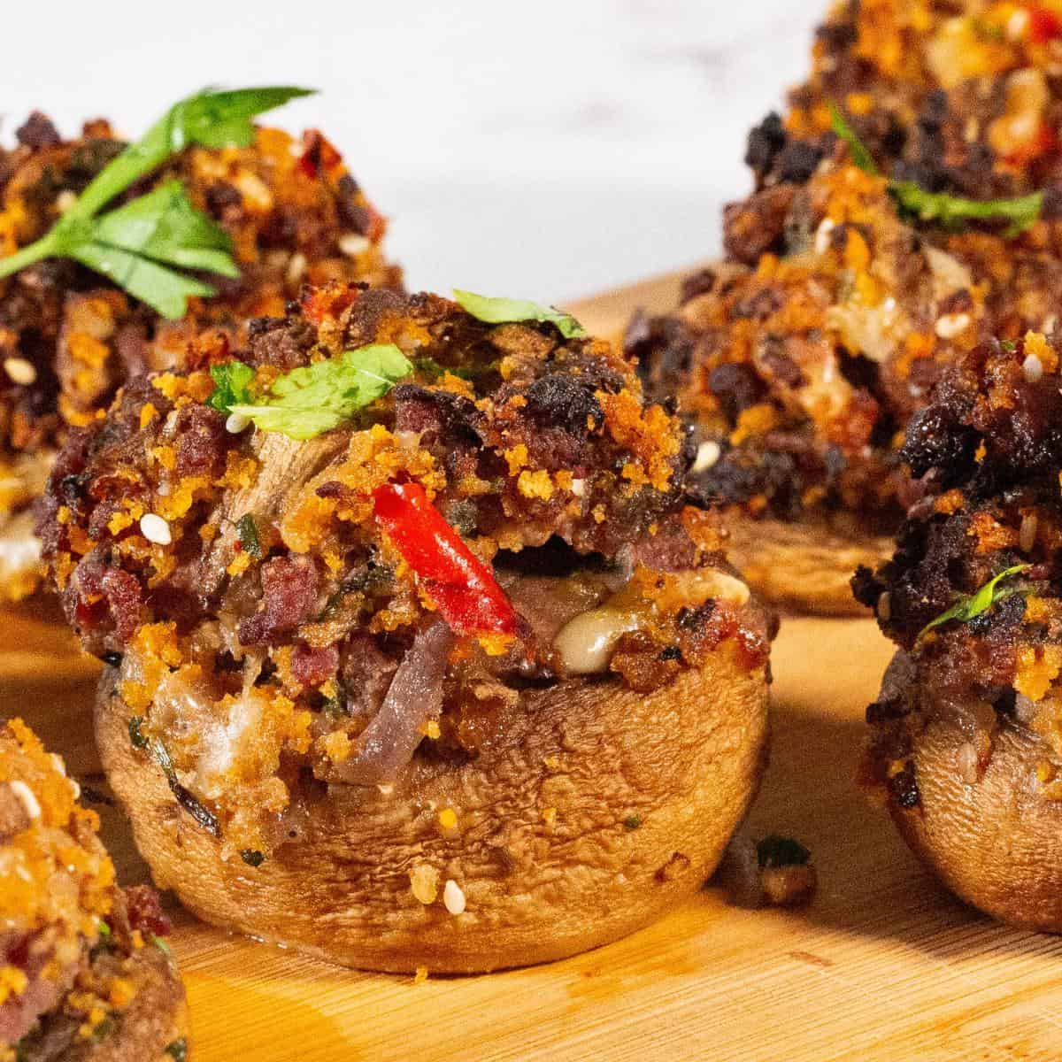 A wooden board with mushrooms and meat.